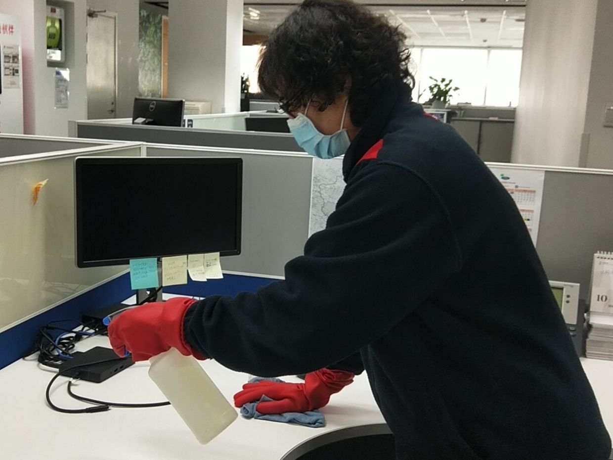 Sodexo staff cleaning office desks with disinfecting solution
