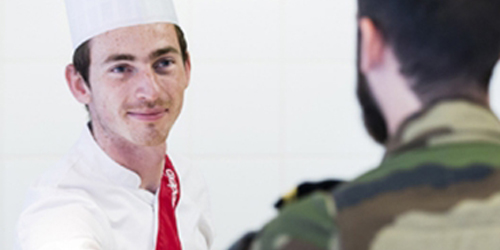 A chef serving food to a man in military uniform